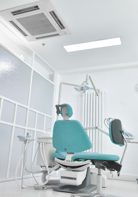 Sillón dental rodeado de material odontológico en una sala vacía de una clínica dental
