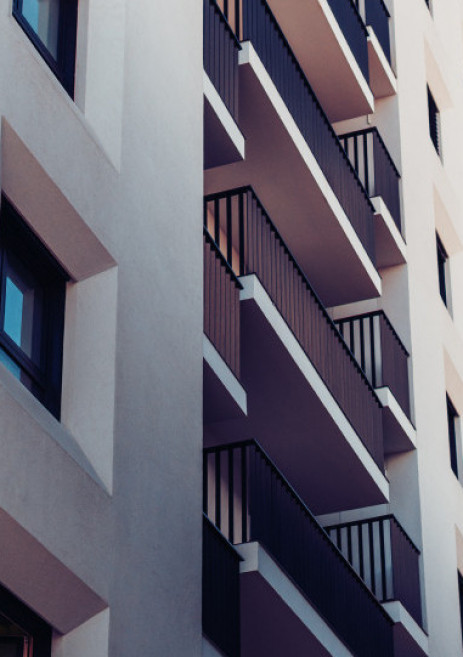 Exterior de un bloque de pisos blanco con balcones de color negro